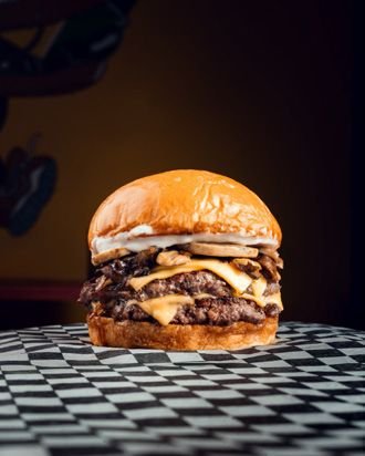 Hamburguesa doble con cheddar apoyada sobre una mesa de ajedrez