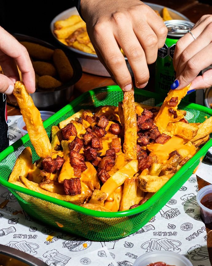 Papas fritas con cheddar derretido y panceta en canasta